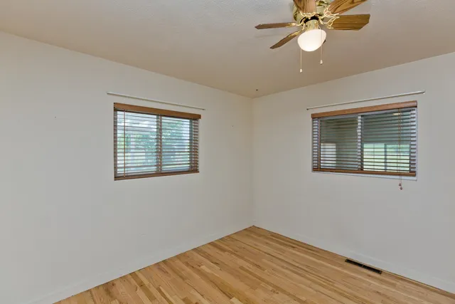 a view of an empty room with a window and wooden floor