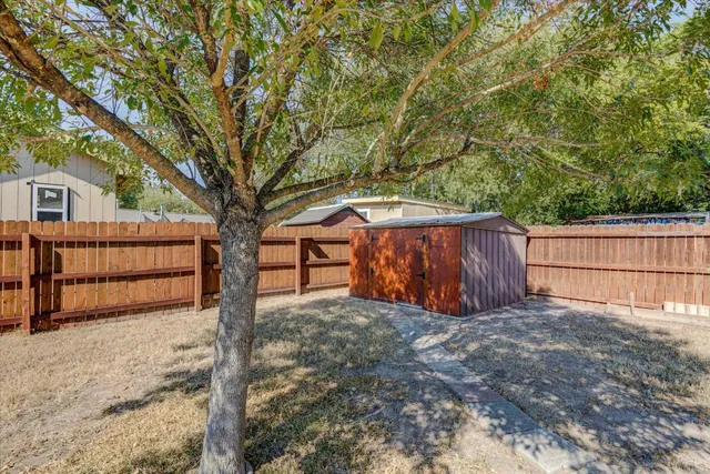 a view of backyard with tree and wooden fence
