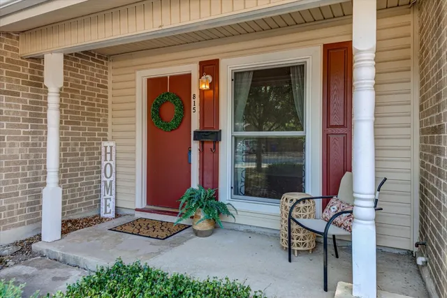 a front view of a house with a garden and chair