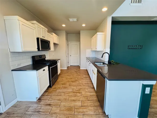a kitchen with granite countertop a sink a stove top oven and cabinetry