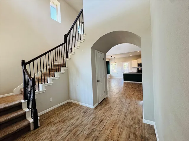 an empty room with a chandelier fan and windows