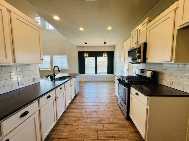 a large kitchen with stainless steel appliances a sink and cabinets