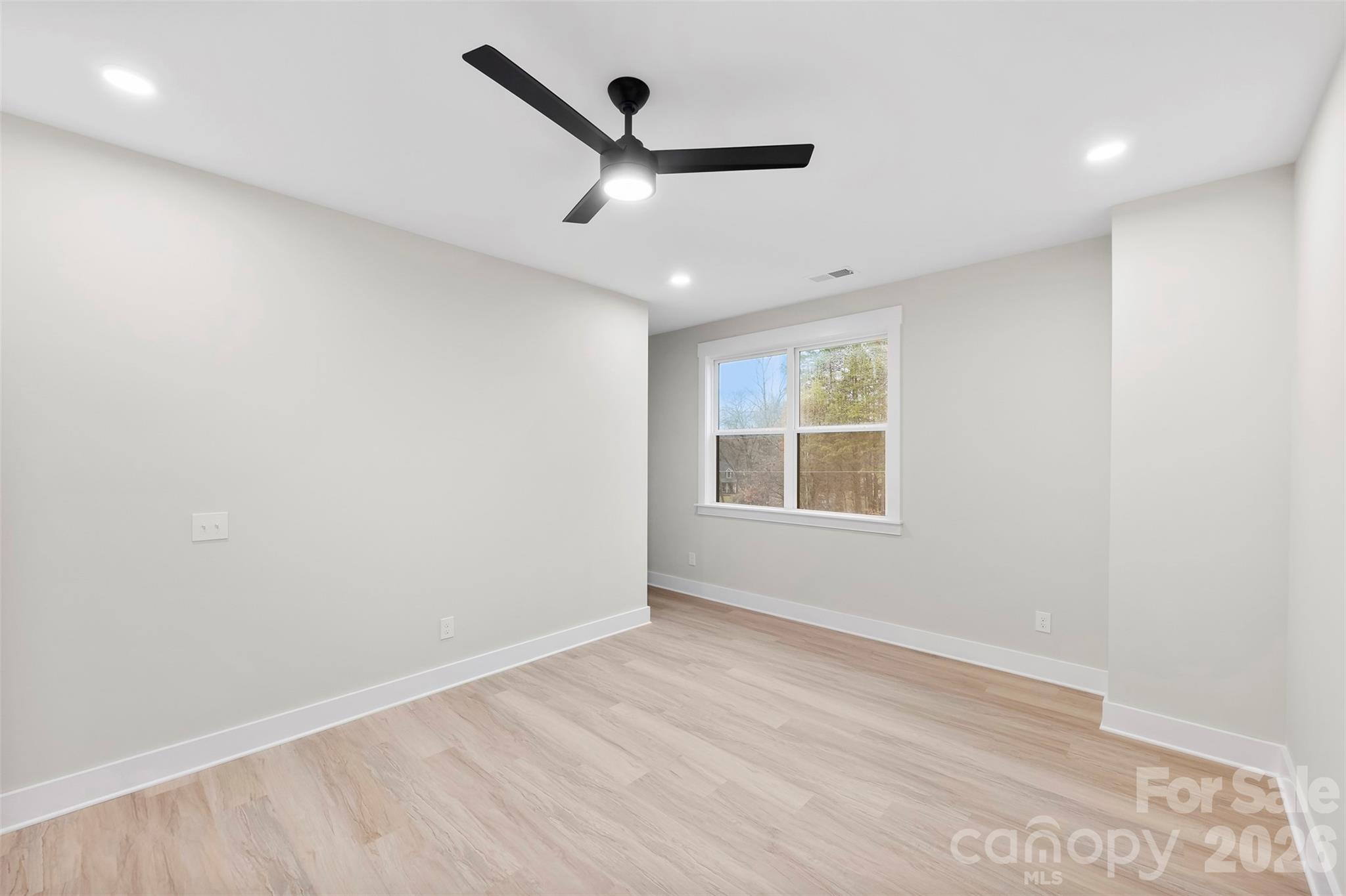 551 Perry Road Troutman, NC 28166 - Photo 24 of 47 an empty room with wooden floor ceiling fan and windows