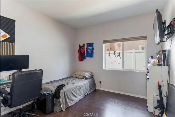a bedroom with a bed table chair and a flat screen tv