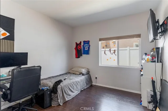 a bedroom with a bed table chair and a flat screen tv