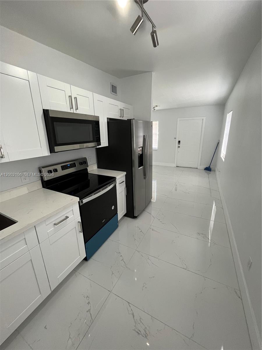 2726 Northwest 4th Court Pompano Beach, FL 33069 - Photo 3 of 11 a kitchen with stainless steel appliances a stove microwave and refrigerator