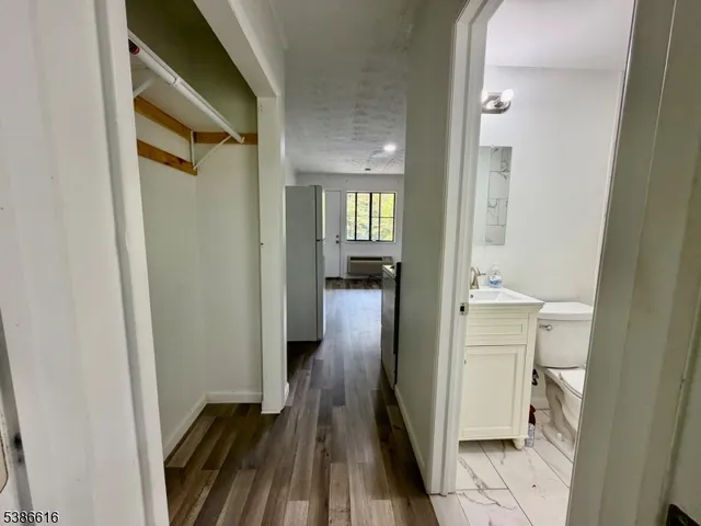 a view of a hallway with wooden floor and a bathroom