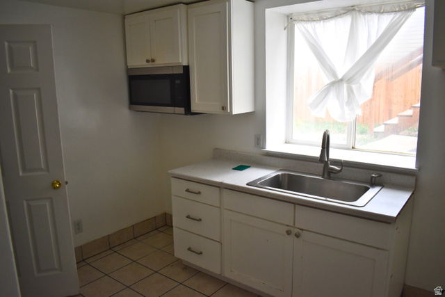 3327 East Windhover Road Eagle Mountain, UT 84005 - Photo 27 of 38 Kitchenette featuring white cabinetry, a stainless steel sink with a modern faucet, an over-the-range microwave, and light-colored tile flooring