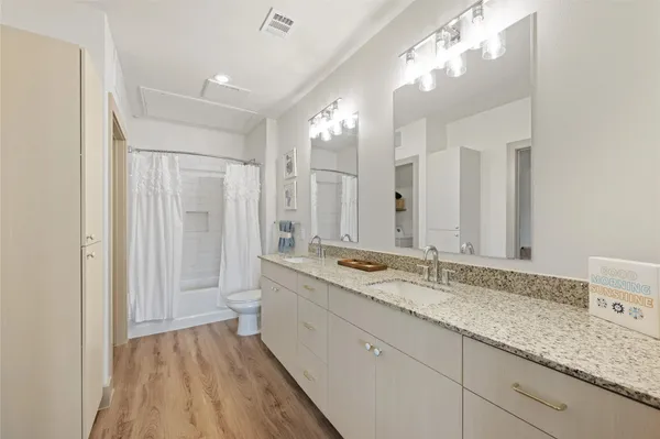 a bathroom with a granite countertop double vanity sink a mirror and a shower