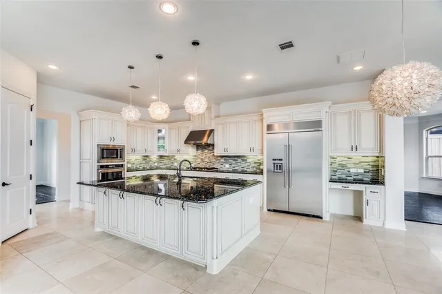 a kitchen with stainless steel appliances kitchen island granite countertop a refrigerator and a sink