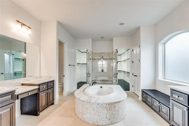 a spacious bathroom with a granite countertop sink mirror vanity bathtub and shower
