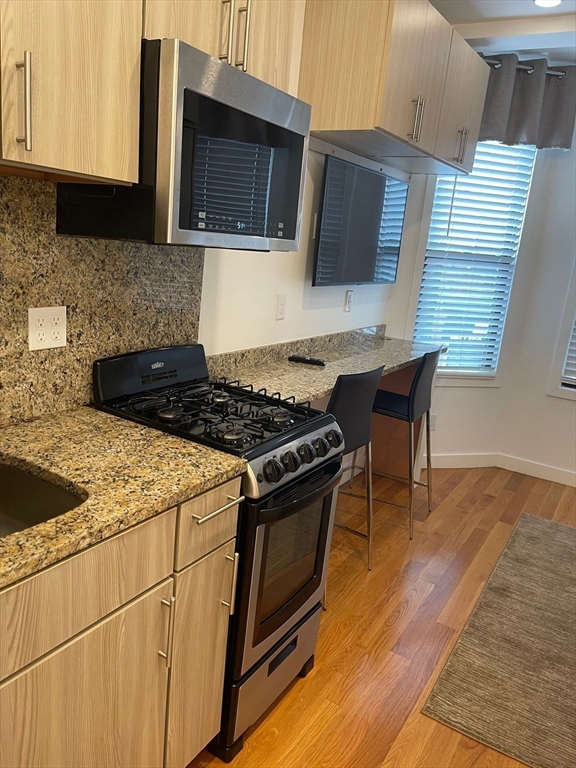 16 5th Street, Unit 8 Chelsea, MA 02150 - Photo 1 of 15 a kitchen with granite countertop a stove and a wooden floor