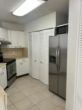 a kitchen with a refrigerator sink and cabinets
