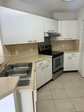 a kitchen with granite countertop white cabinets and white appliances