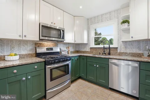 a kitchen with granite countertop a stove top oven microwave and cabinets