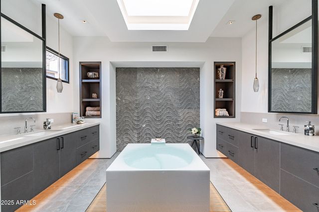 a spacious bathroom with a double vanity sink a large mirror and a bathtub