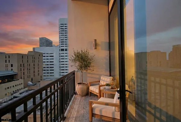a view of balcony with a couple of cars parked on road in front of house