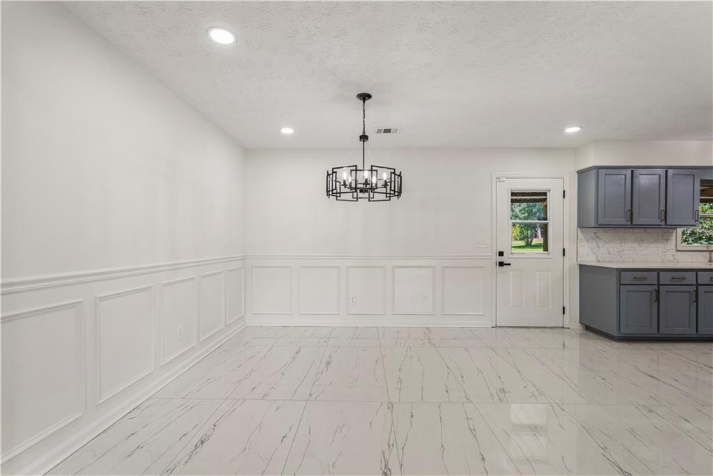 766 Lee Road Phenix City, AL 36870 - Photo 6 of 30 Unfurnished dining area with a decorative wall, a chandelier, recessed lighting, light marble finish flooring, and wainscoting