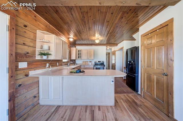 19350 Lemesany Road Calhan, CO 80808 - Photo 18 of 46 Kitchen with wood ceiling, breakfast bar, black fridge, tile floors, dishwasher, and electric stove