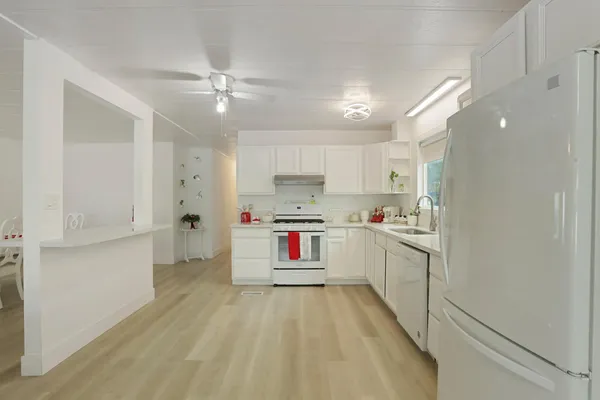 a kitchen with a refrigerator a sink and dishwasher with white cabinets