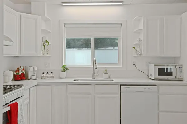 a kitchen with stainless steel appliances granite countertop a sink a stove and white cabinets
