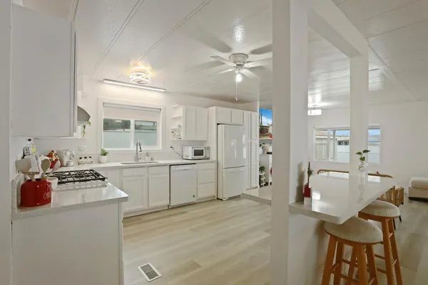 a kitchen with a refrigerator a stove top oven a sink dishwasher and dining table with wooden floor