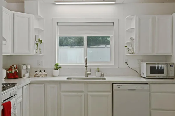 a kitchen with stainless steel appliances white cabinets and a window