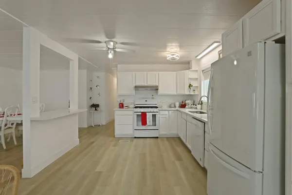 a kitchen with refrigerator a stove and white cabinets