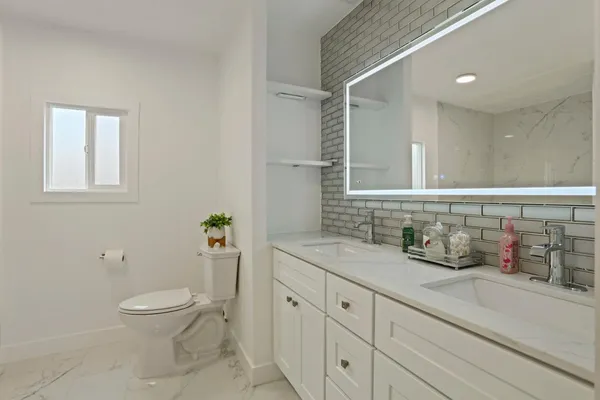 a bathroom with a granite countertop sink a toilet and a mirror
