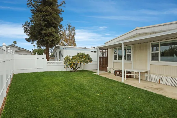 a view of a backyard with table and chairs and large trees