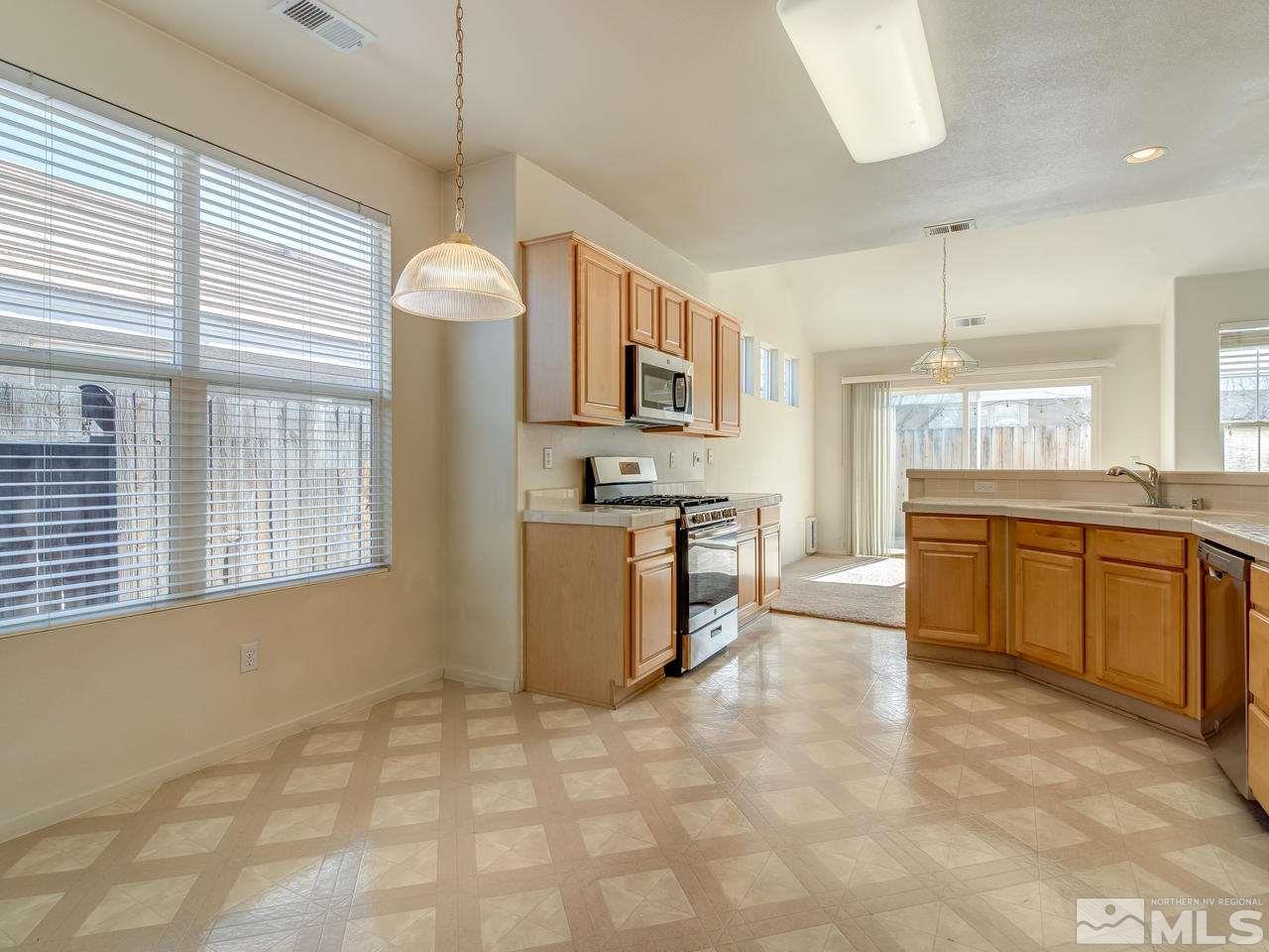 9647 Truckee Meadows Place Reno, NV 89521 - Photo 10 of 25 a large kitchen with kitchen island granite countertop a stove a sink a window and stainless steel appliances