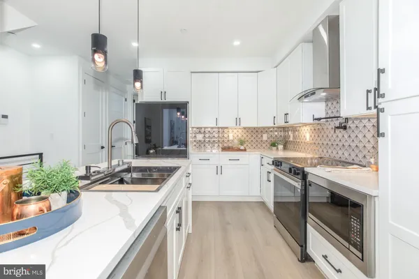 a large kitchen with a large counter top space a sink stainless steel appliances and cabinets