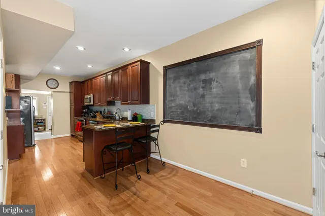 a living room with stainless steel appliances kitchen island granite countertop furniture a rug and a wooden floor