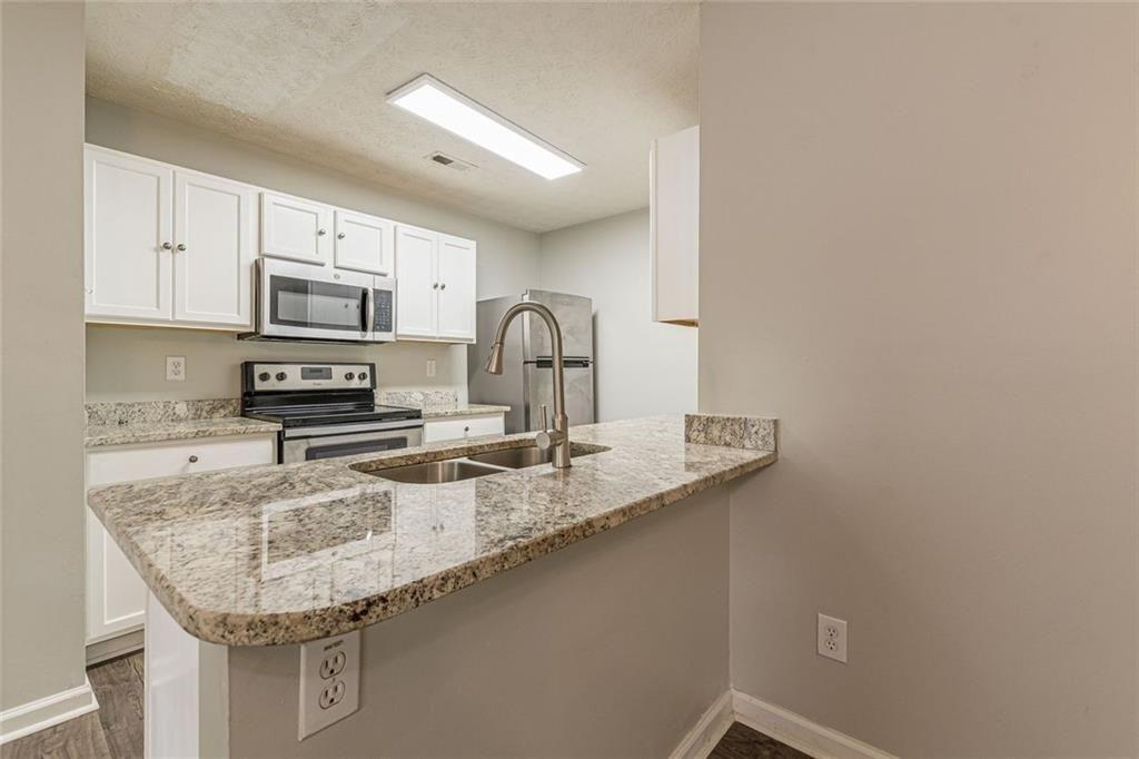 3151 Kingswood Glen Decatur, GA 30034 - Photo 11 of 38 a kitchen with granite countertop a sink a stove and cabinets