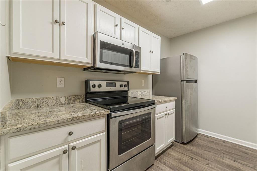 3151 Kingswood Glen Decatur, GA 30034 - Photo 13 of 38 a kitchen with white cabinets stainless steel appliances and wooden floor