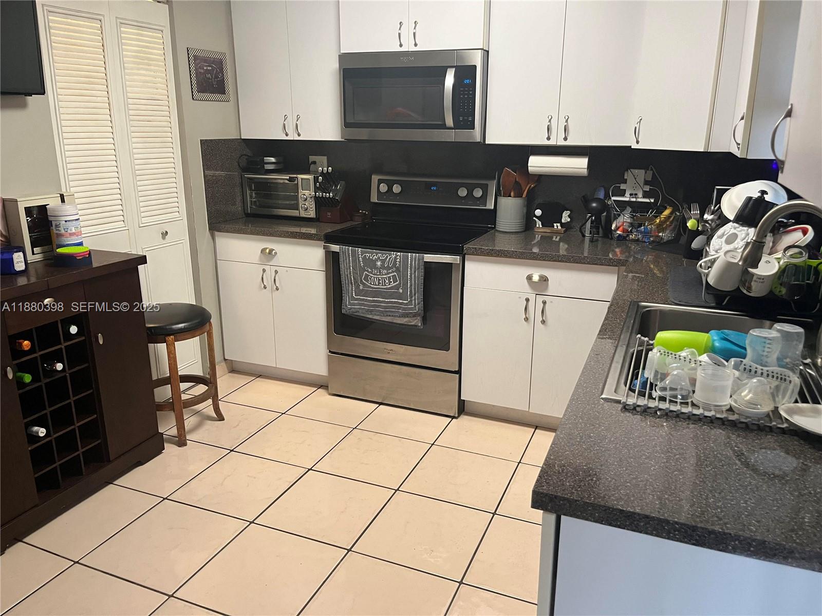 6275 Southwest 130th Avenue, Unit 805 Miami, FL 33183 - Photo 3 of 12 a kitchen with stainless steel appliances a sink a stove a microwave a refrigerator and cabinets