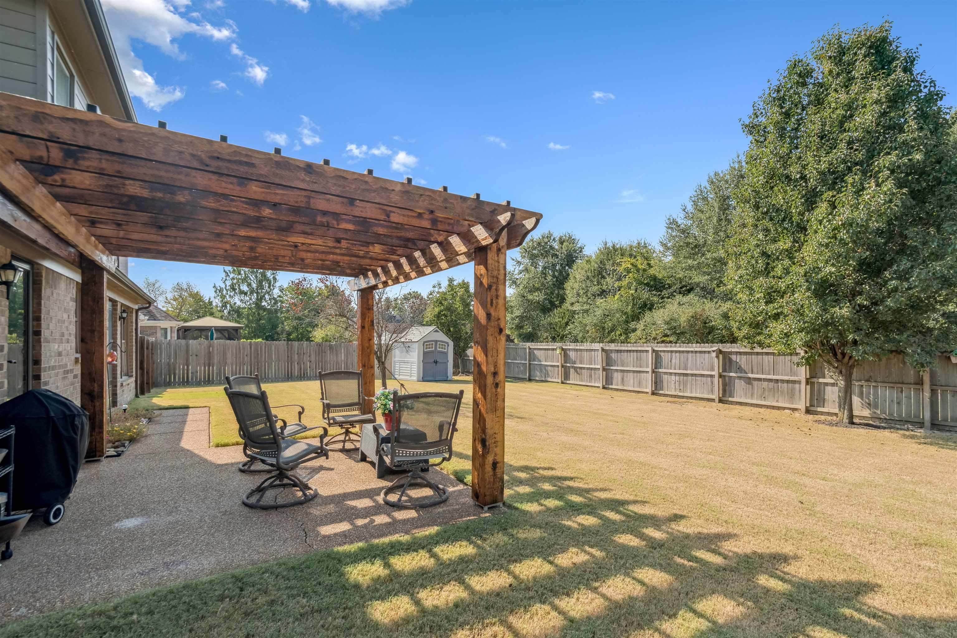 1337 Hunters Mill Trail Collierville, TN 38017 - Photo 21 of 25 a view of a patio with table and chairs under an umbrella with large trees