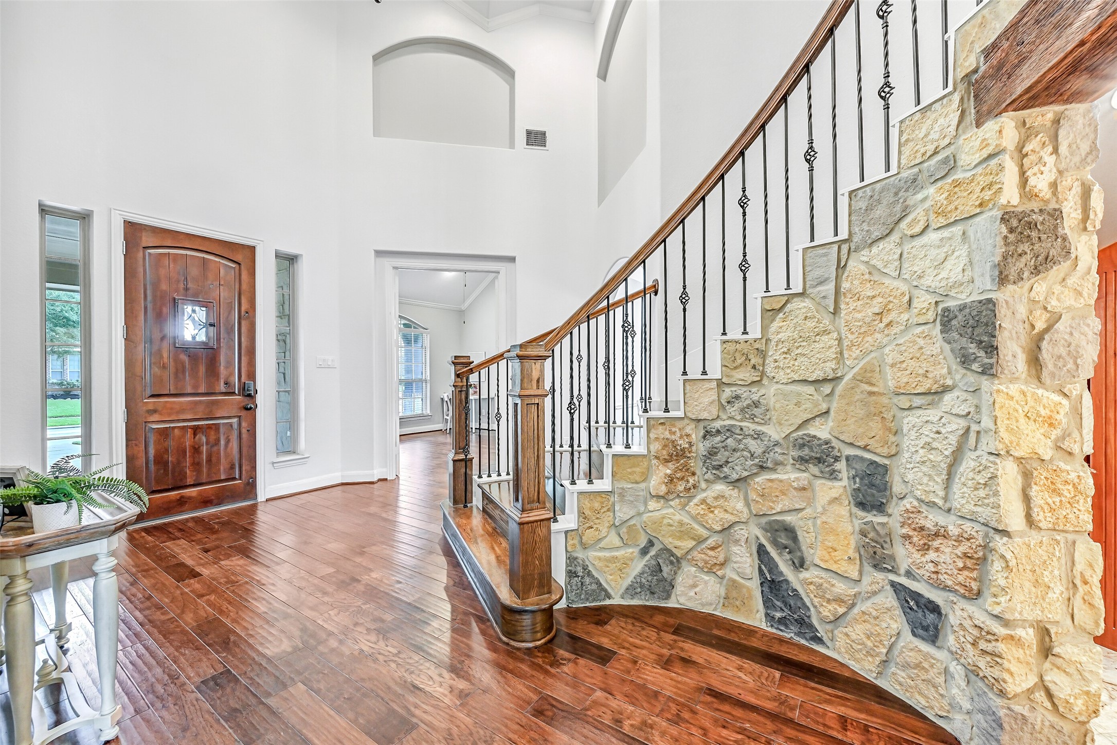 1008 Point Isabel Lane Friendswood, TX 77546 - Photo 6 of 50 From within, the foyer showcases its scale with tall ceilings, natural light, a speakeasy style door, and detailed finishes, anchored by the curved staircase and stone accent wall that adds warmth and character and conceals the wine grotto.