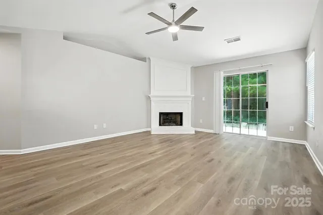 a view of a livingroom with a fireplace a ceiling fan and kitchen view