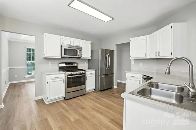 a kitchen with stainless steel appliances granite countertop a stove top oven a sink dishwasher and a refrigerator with wooden cabinets