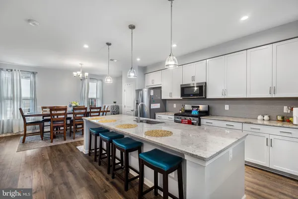 a kitchen with stainless steel appliances granite countertop a stove a sink a microwave a center island and chairs