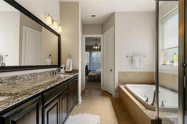 a bathroom with a granite countertop sink a mirror and a bathtub