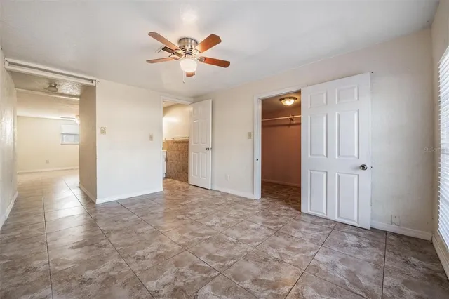 an empty room to closet and a ceiling fan