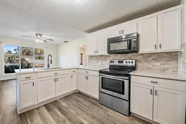 a kitchen with granite countertop white cabinets white stainless steel appliances and a sink