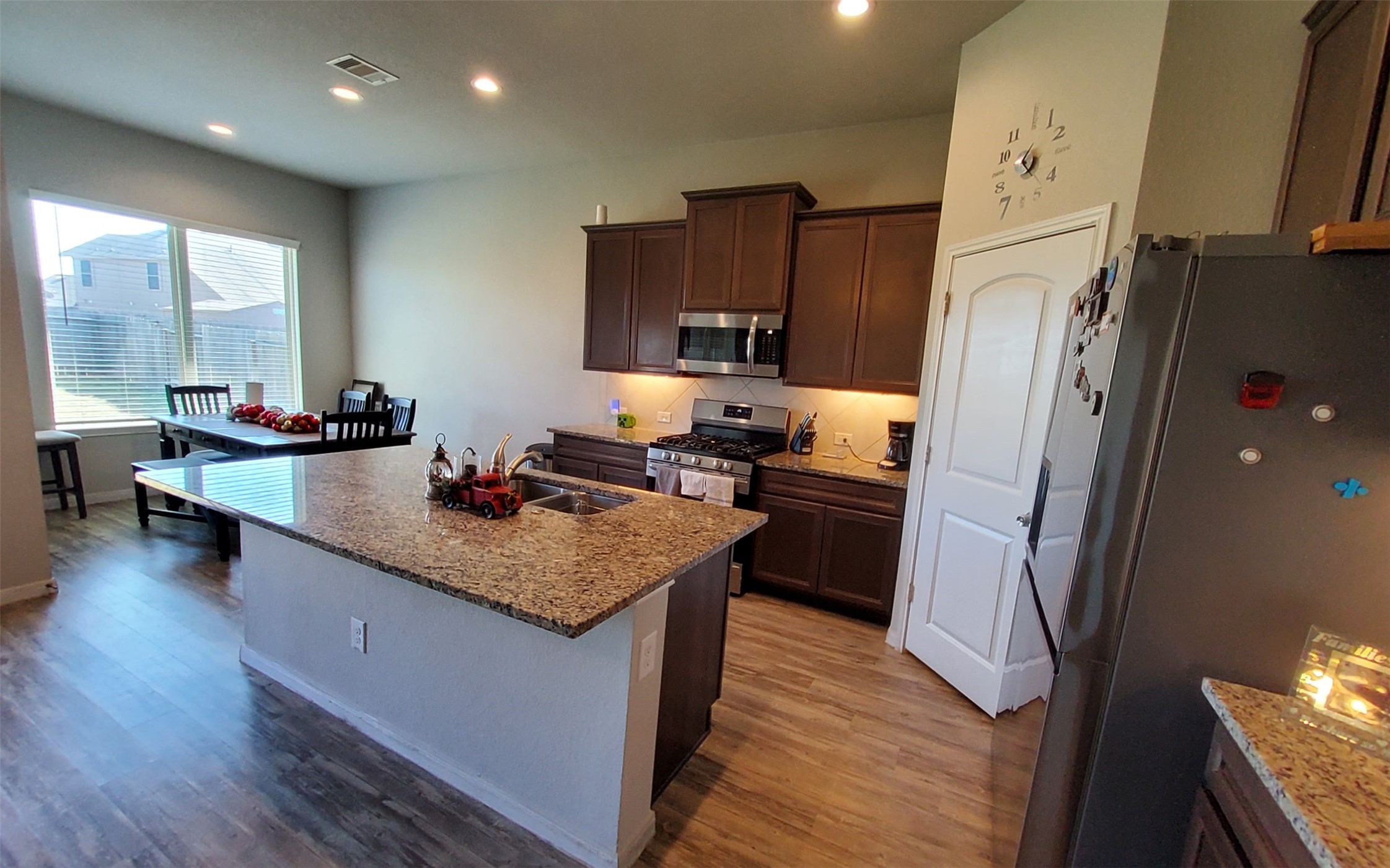 24418 Hollow Gate Meadow Court Spring, TX 77389 - Photo 17 of 45 a kitchen with stainless steel appliances granite countertop a refrigerator a sink dishwasher a stove and a dining table with wooden floor
