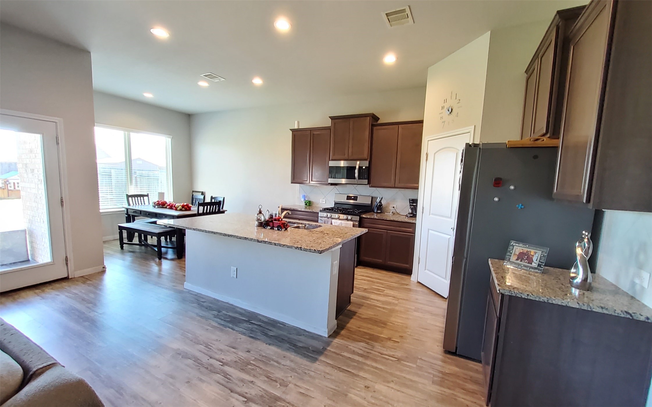 24418 Hollow Gate Meadow Court Spring, TX 77389 - Photo 20 of 45 a kitchen with stainless steel appliances a refrigerator a stove a sink dishwasher and a dining table with wooden floor