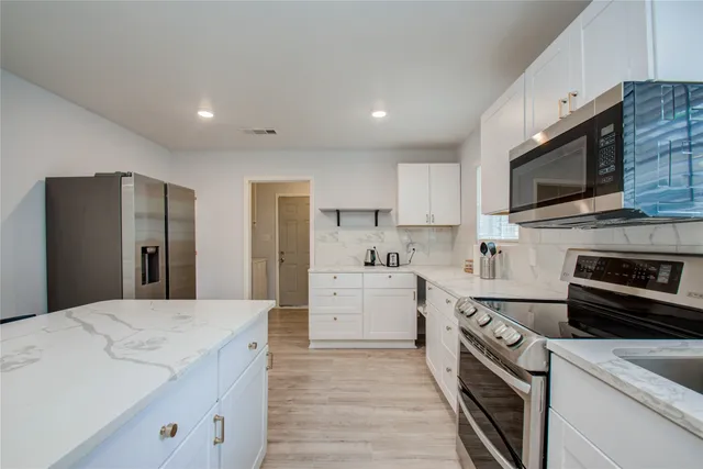 a open kitchen with stainless steel appliances granite countertop a stove a sink and a refrigerator