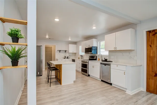 a kitchen with white cabinets and stainless steel appliances