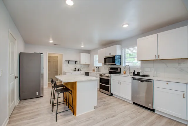 a kitchen with white cabinets stainless steel appliances and wooden floor