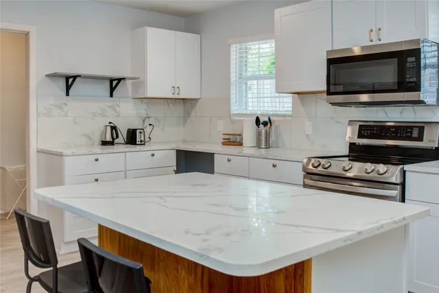 a kitchen with stainless steel appliances a stove a sink a microwave and cabinets